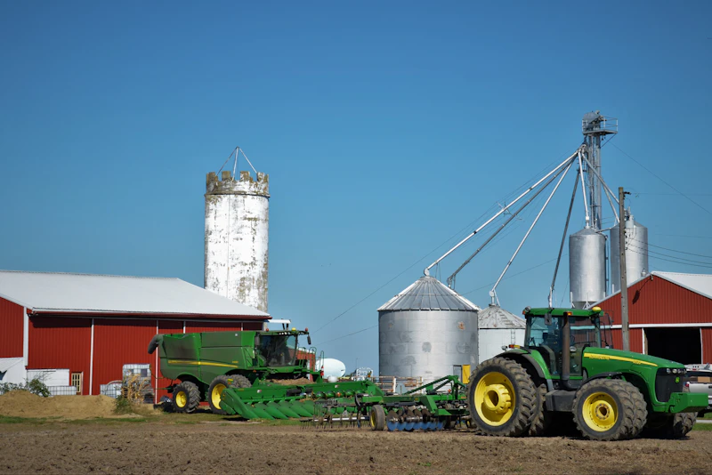 Tractor pulling trailer with grain silo in background
