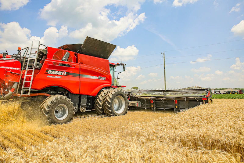 Red combine harvester driving through a wheat field